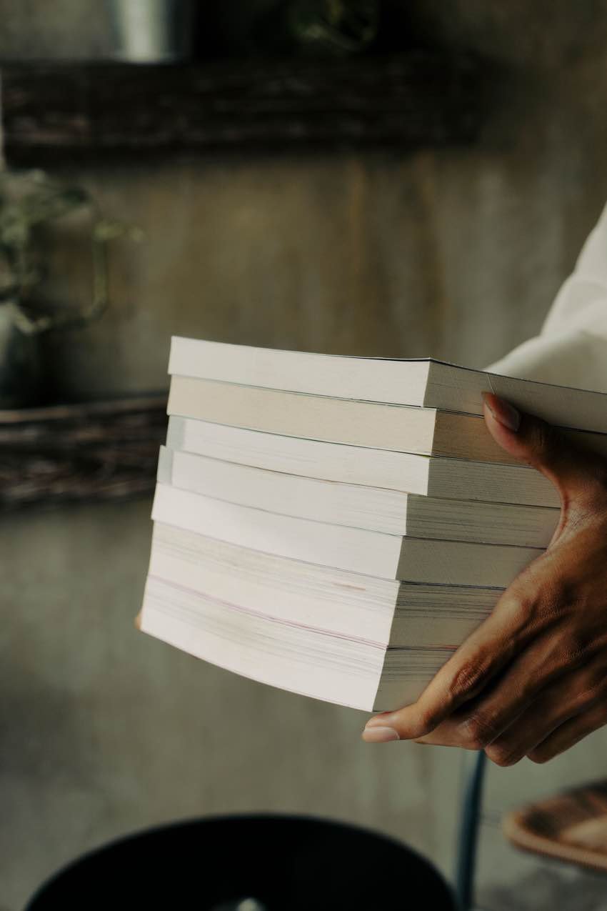 Elinde bir yığın kitap taşıyan bir kişi